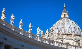 Decorazione di statue sulla cattedrale di san pietro con la cupola sullo sfondo - roma, italia foto