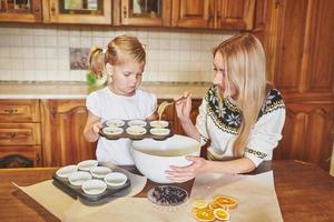 una piccola bella ragazza sta preparando i cupcakes foto