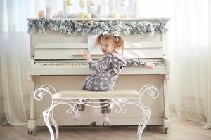 la bambina felice suona il pianoforte il giorno di natale foto