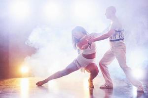 abili ballerini si esibiscono nella stanza buia sotto la luce e il fumo del concerto. coppia sensuale che esegue una danza contemporanea artistica ed emotiva foto