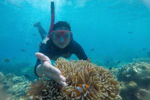 giovane donna che fa snorkeling su una bellissima barriera corallina con pesci sulla spiaggia di karimun jawa foto