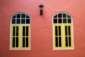 due finestre gialle con lampadario vintage attaccato alla parete marrone foto