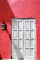 vecchia porta bianca con lampadario vintage appeso al muro rosso