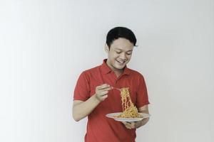 ritratto di felice giovane asiatico gode di noodles. mangiare il concetto di pranzo. foto
