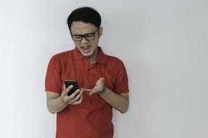 il giovane asiatico intelligente è confuso e sottolinea quando guarda lo smartphone sullo sfondo dello studio. foto