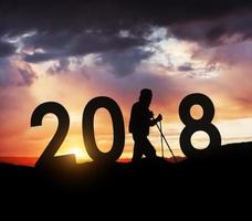 silhouette giovane escursionista uomo per il nuovo anno 2018 sfondo del tramonto foto