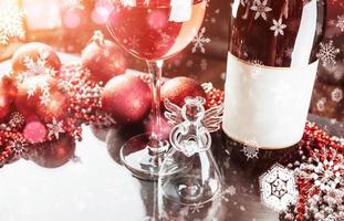 natale e capodanno. decorazioni festive, bottiglia di vino rosso e vetro sullo sfondo scuro. felice anno nuovo e natale. bokeh luce effetto morbido foto