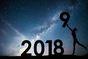 ragazza di sagoma. felice anno nuovo 2018. sfondo della Via Lattea su una stella luminosa tonalità del cielo scuro. cambio di concetto dal 2017 al 2018 foto