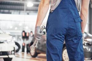 mani del meccanico di automobili con una chiave inglese in garage foto