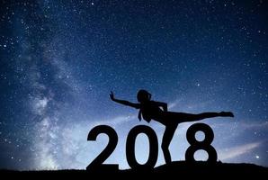 la ragazza della siluetta si sta rilassando sullo sfondo del nuovo anno 2018 della galassia della Via Lattea su un tono del cielo scuro di una stella luminosa foto