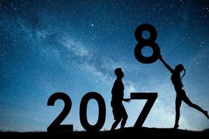 sagoma giovane ragazza e ragazzo. felice anno nuovo 2018. sfondo della Via Lattea su una stella luminosa tonalità del cielo scuro. cambio di concetto dal 2017 al 2018 foto