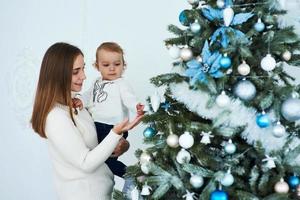 famiglia felice madre e bambino decorano l'albero di natale foto