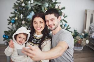 famiglia riunita attorno a un albero di natale, utilizzando un tablet foto