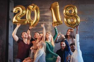 un gruppo di giovani allegri tiene i numeri che indicano l'arrivo di un nuovo anno 2018. la festa è dedicata alla celebrazione del nuovo anno. concetti sullo stile di vita insieme giovanile foto