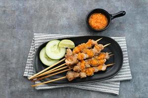 sate taichan, satay di pollo alla griglia senza salsa di arachidi o salsa di soia. servito su piatto con salsa di peperoncino. foto