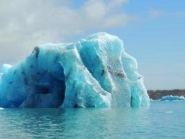 iceberg blu brillante turchese che galleggia nell'acqua fredda blu del mare del nord foto