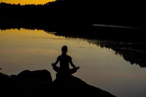 sagome di una donna che fa yoga al tramonto foto