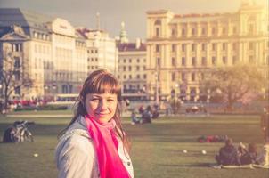 giovane ragazza viaggiatore con giacca bianca che distoglie lo sguardo e sorride nel parco sigmund freud del centro storico di vienna foto