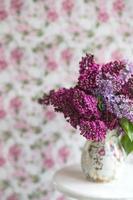 bouquet di lillà viola in un vaso. natura morta con rami fioriti di lillà in vasi. biglietto di auguri mock up. spazio per il testo. foto