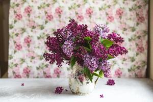 bouquet di lillà viola in un vaso. natura morta con rami fioriti di lillà in vasi. foto