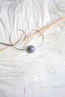 collana in pietra naturale con montature in argento con fiori lilla viola viola su piuma di struzzo bianca. accessori in argento. foto