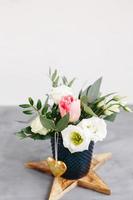 bouquet primaverile in vaso di vetro trasparente su stella di legno. rose, tulipani e lisianthus. foto