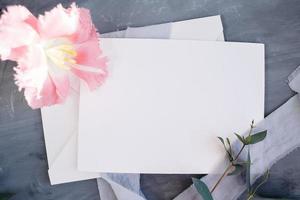 spazio di copia su carta bianca. cornice con fiori. nastro di seta. sfondo grigio. bouquet semplice. biglietto d'auguri. foto