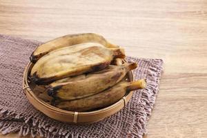 pisang kukus o banana al vapore, cibo tradizionale indonesiano, uno spuntino sano. servito su tavola di legno. avvicinamento. foto