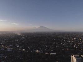 vista aerea del monte merapi al tramonto e della città di yogyakarta, indonesia. città con vista sullo sfondo delle montagne. foto