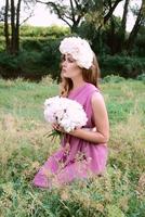 bella donna caucasica con una corona di peonie in testa. concetto di primavera, fiore, fata foto