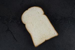 fetta di pane bianco isolata su sfondo di pietra nera. foto