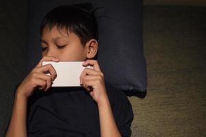 ragazzo asiatico addormentato mentre giocava su uno smartphone foto