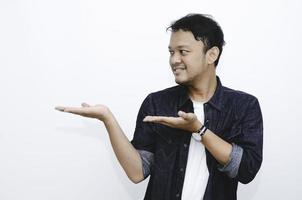 sorriso di giovane uomo asiatico in camicia bianca con punto della mano su uno spazio vuoto foto