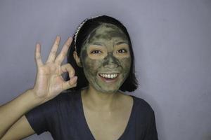 Sorridi alle donne asiatiche che sorridono quando usa la maschera per il viso di bellezza foto