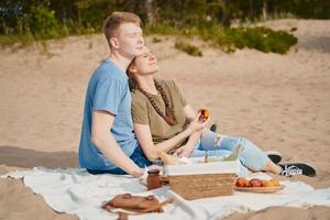 picnic in spiaggia con cibo e bevande. ragazzo e ragazza che prendono il sole foto