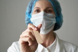 dottoressa in maschera medica e controllo uniforme delle condizioni della gola. protezione dalle malattie, foto