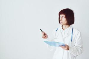 la dottoressa adulta sta su uno sfondo bianco mostra, fa un gesto della mano foto