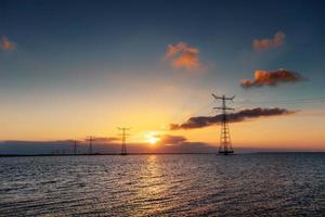 linea elettrica sopra l'acqua durante un fantastico tramonto foto