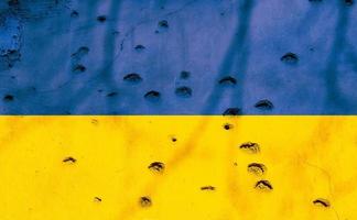 bandiera ucraina con fori di proiettile sulla facciata di un edificio residenziale come sfondo. bandiera dell'ucraina. fermate la guerra. conflitti armati. definanziare gli eserciti. no alla guerra. foto