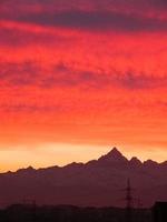 tramonto rosso con nuvole e skyline di montagne foto