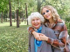 donna anziana con la giovane figlia che cammina all'aperto in primavera. famiglia, generazione, cura, amore, concetto di vaccinazione foto