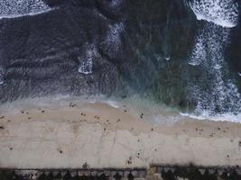 vista aerea del drone della vacanza nella spiaggia di gunung kidul, in indonesia con oceano, barche, spiaggia e persone. foto