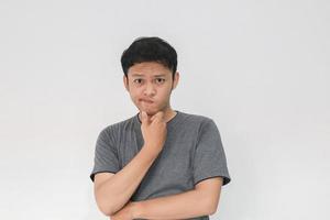 il giovane uomo asiatico indossa una camicia grigia con un gesto di idea di pensiero e sguardo foto