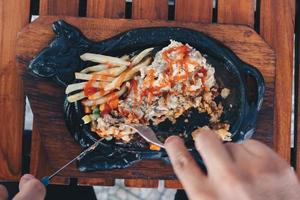 a mano tagliare una bistecca di pollo croccante piastra calda con salsa barbecue e patate foto