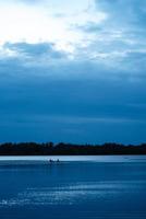 tramonto blu sul fiume con sagome foto