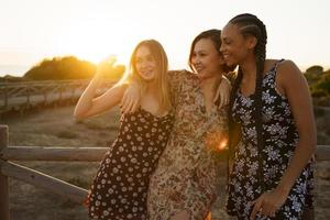 donne diverse sorridenti che si abbracciano sulla passerella di legno foto
