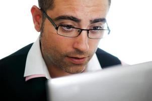 uomo d'affari di successo con gli occhiali che indossano giubbotto e camicia rosa guardando un piccolo computer foto