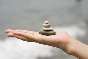 mucchio di ghiaia nelle mani della donna con lo sfondo del mare foto