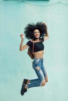 giovane donna mista con capelli afro che salta all'aperto.