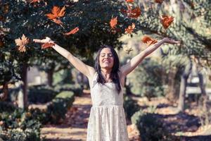 bella ragazza bruna con foglie che cadono in autunno foto